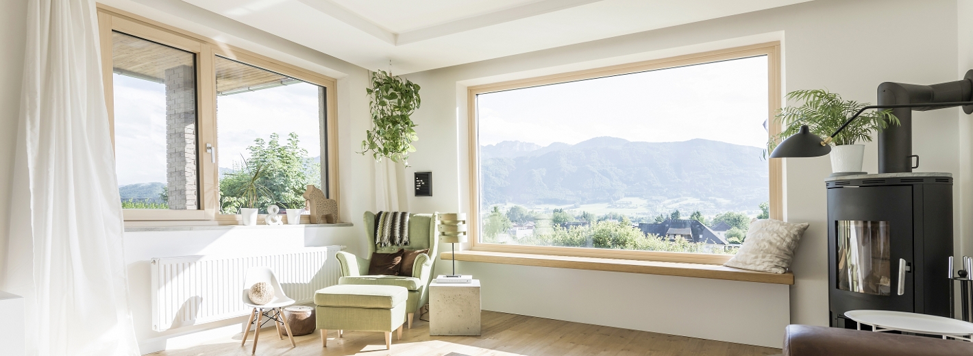 modernes Wohnzimmer mit zwei großen Fenstern mit schönen Ausblick in die Natur.