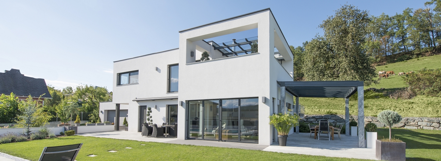 Modernes Haus mit großen Fenstern und Terrassentüren.