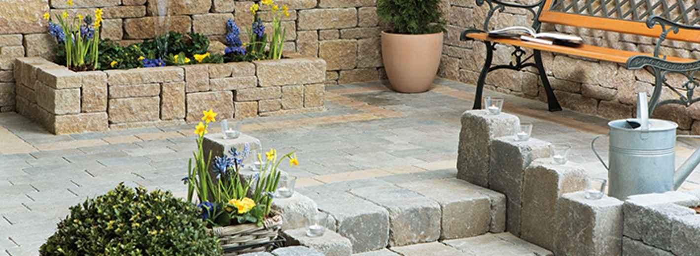 Terrasse mit Casafino Steinen gestaltet mit kleinem Hochbeet, Stiegen und Blumentöpfen