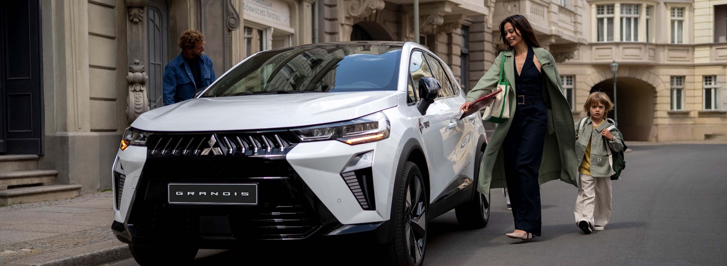 Familie steigt in einen weißen Mitsubishi Grandis ein.