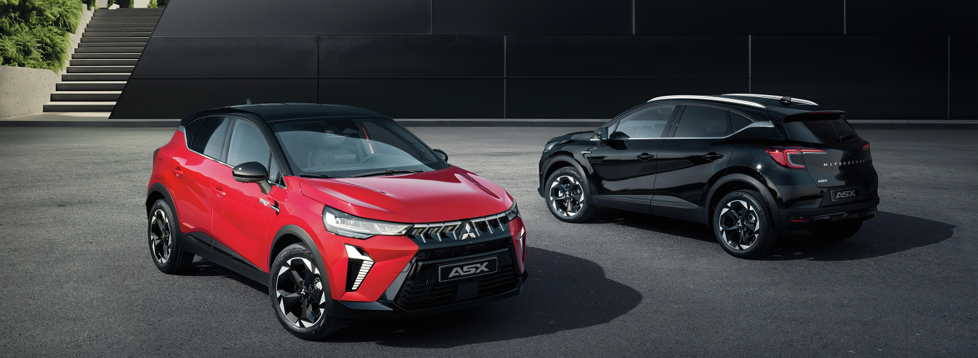 Zwei Autos des Motells Mitsubishi ASX parken vor einem modernen Gebäude. Das linke Fahrzeug ist Rot und von vorne sichtbar. Das rechte Fahrzeug hat die Farbe Schwarz und steht in seitlicher Rückansicht geparkt.
