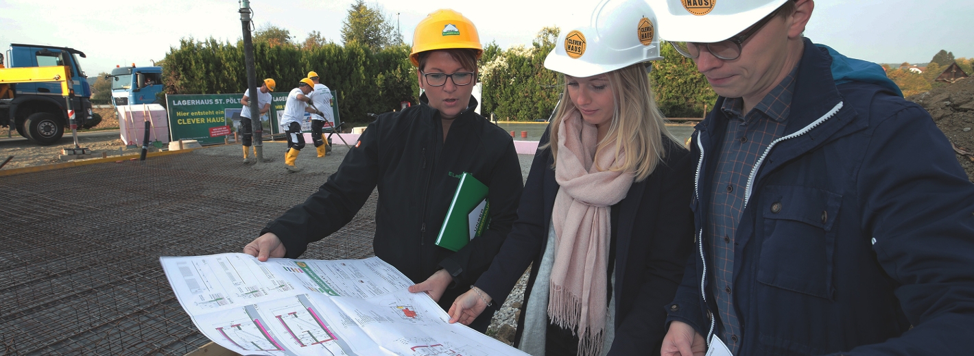 Lagerhaus Planerin bespricht mit Bauherren Bauplan auf der Baustelle