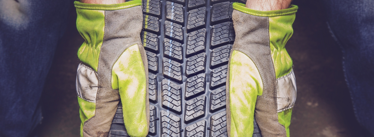 Hände in Handschuhe halten Winterreifen