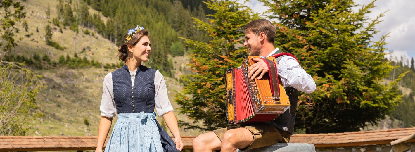 Frau im Dirndl und Mann in Lederhose musizieren
