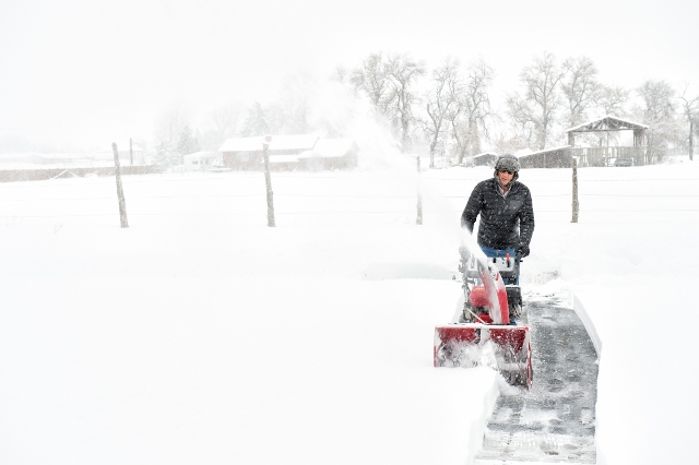 Mann räumt Schnee mit Schneefräse