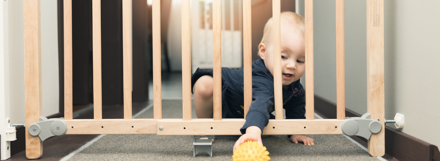 Baby sitzt vor Schutzgitter