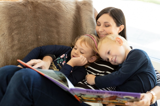 Mutter mit ihren Kinder beim Vorlesen im neuen Wohnzimmer