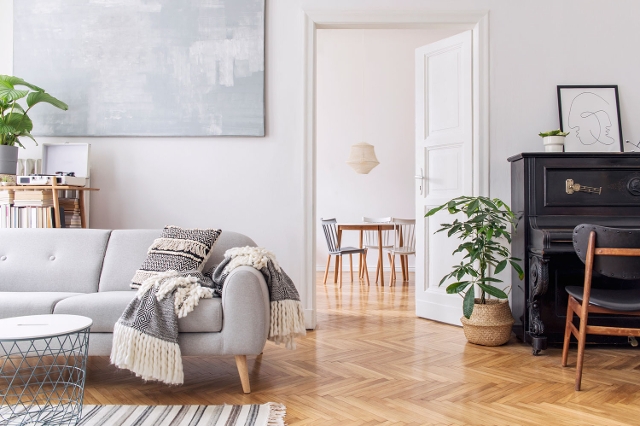 Helles Wohnzimmer mit Holzboden, Sofa, Pflanzen und angrenzendem Essbereich