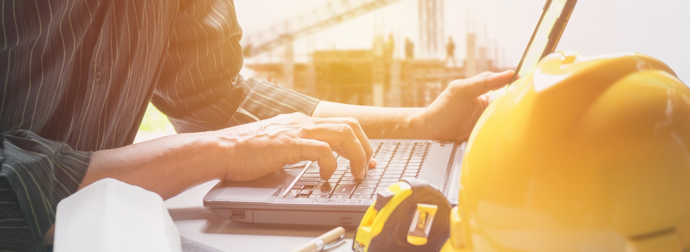 Bauarbeiter sitzt vor Laptop