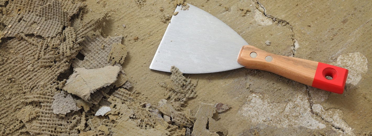 Spachtel liegt neben Teppichbodenresten