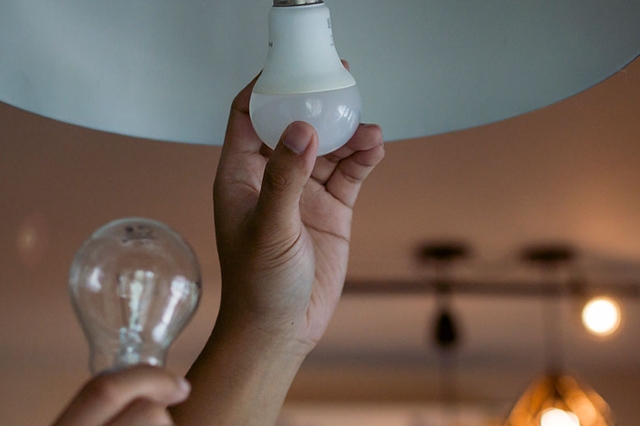 Hände halten eine Glühbirne und eine LED-Lampe