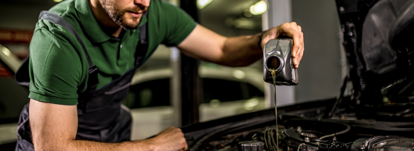 Mann der Motoröl ins Auto füllt