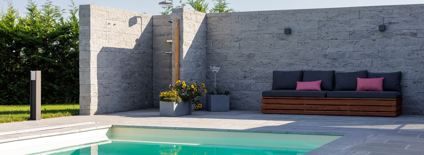 Foto von Steinmauer, Pool mit schönem Pflaster und Couch.