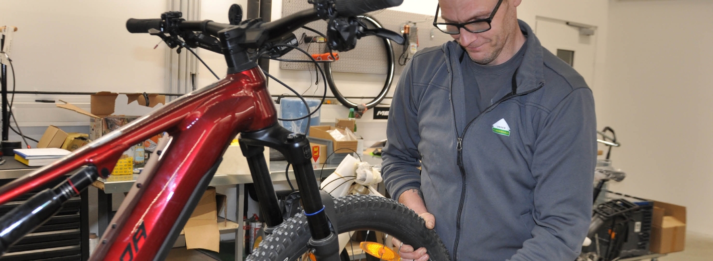 Fahrradmechaniker repariert ein E-Bike und arbeitet am Vorderrad