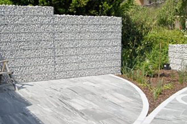 Gemütliche Sitzecke mit Steinmauer im Hintergrund und schönem, gepflastertem Boden aus Marmor