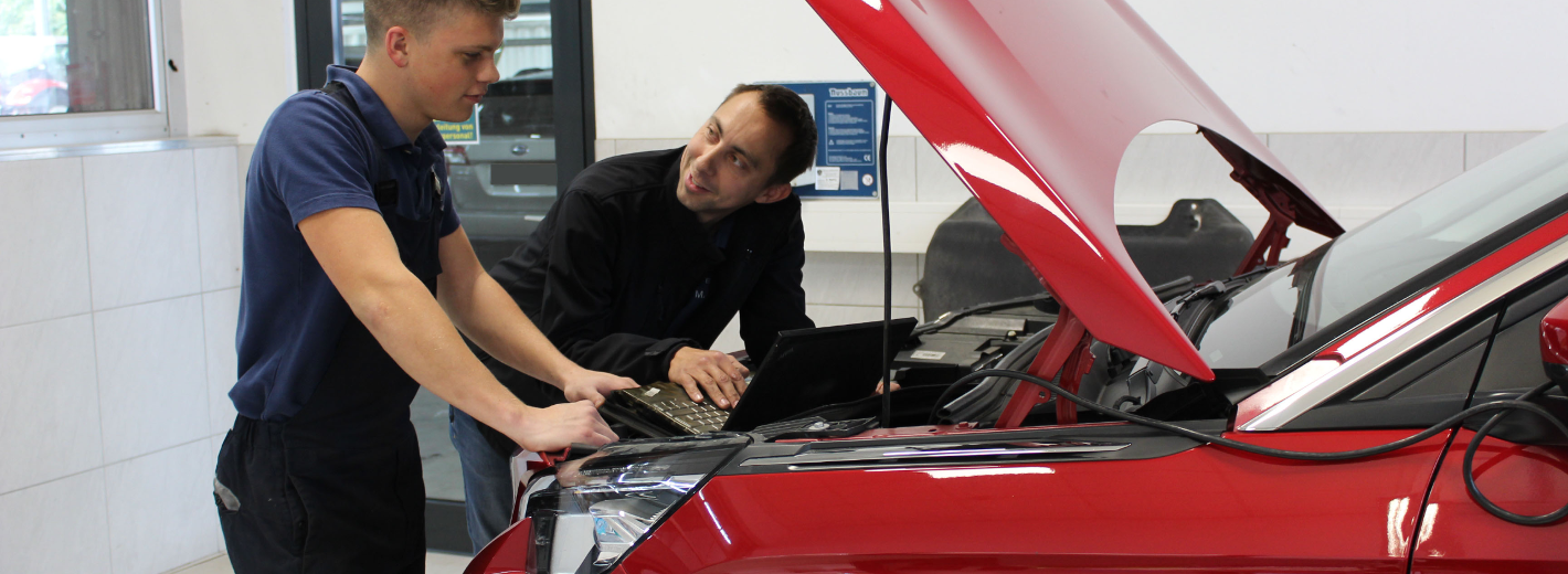 Lagerhaus Mechaniker und Lehrling bei der Reparatur eines Autos in der Lagerhaus Fachwerkstätte