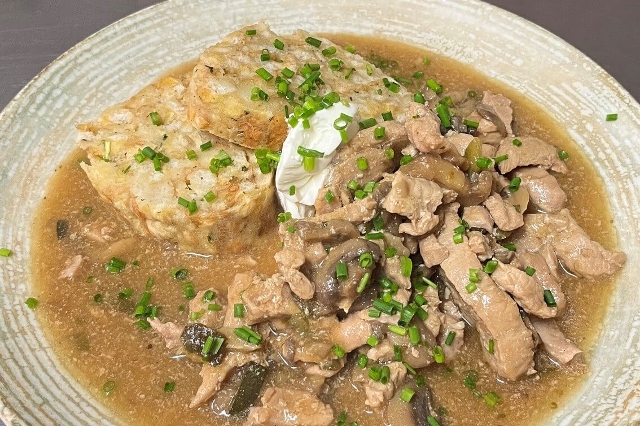 Auf dem Bild ist eine Portion eines frischen Mittagsmenüs des Lagerhaus Gasthauses zur Ähre zu sehen. Es handelt sich um ein Putengeschnetzeltes mit Champignions und Serviettenknödel. Als Deko dienen Schnittlauch und ein Tupfer Rahm.