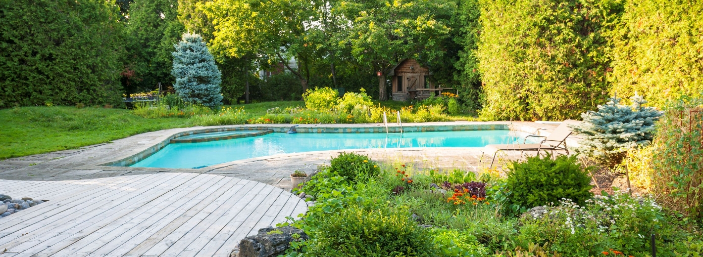 Garten mit Terrasse aus Holz und Pool im Hintergrund