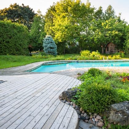 Garten mit Terrasse aus Holz und Pool im Hintergrund