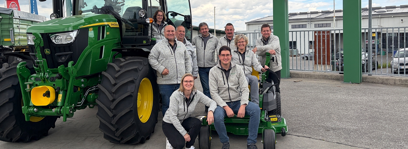 Team von Lagerhaus Zwettl Landtechnik W4 vor einem John-Deere-Traktor am Betriebsstandort in Zwettl.