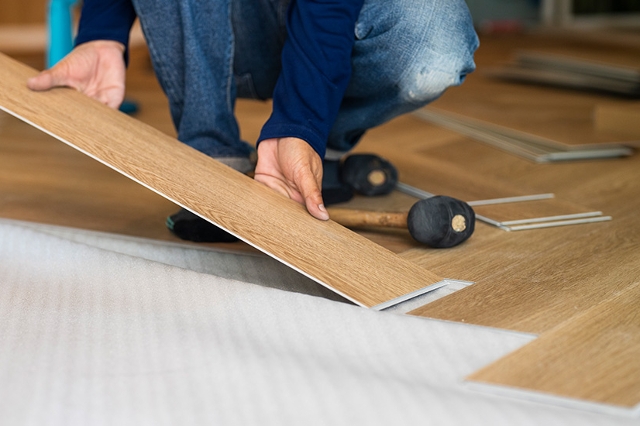 Person verlegt Vinylboden mit Klicksystem im Innenraum