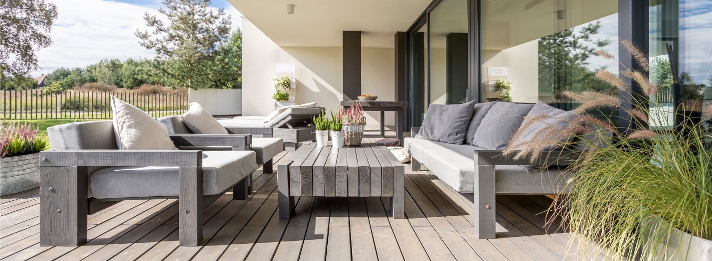 Terrasse mit braun-grauem Bodenbelag und Loungemöbeln
