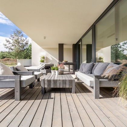Terrasse mit braun-grauem Bodenbelag und Loungemöbeln