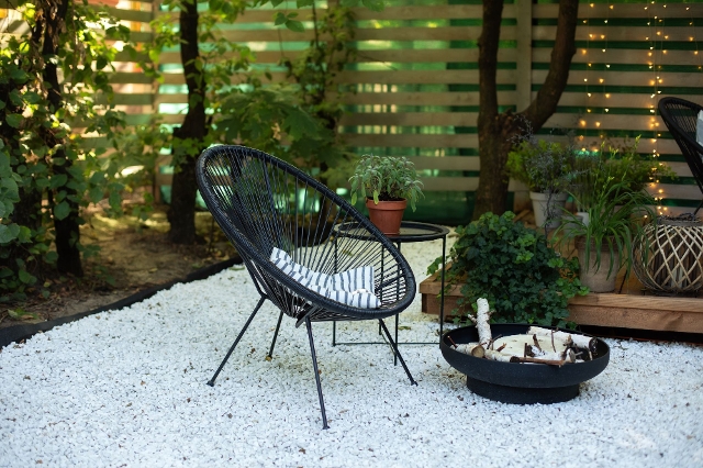 Terrasse mit Kieselsteinen als Bodenbelag und schwarzem Stuhl