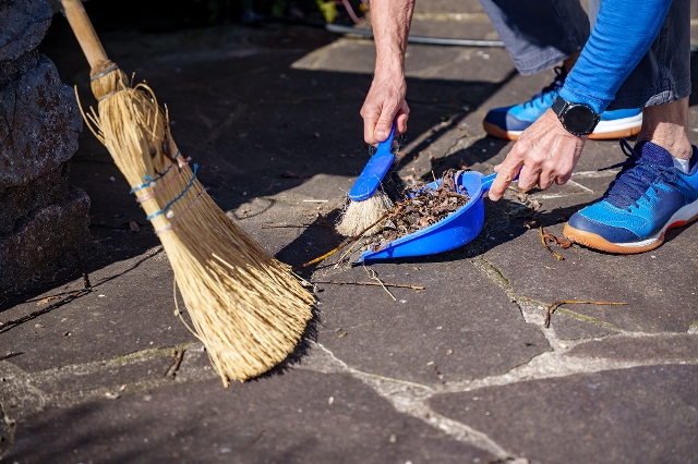Mann fegt Terrassenplatten mit Besen