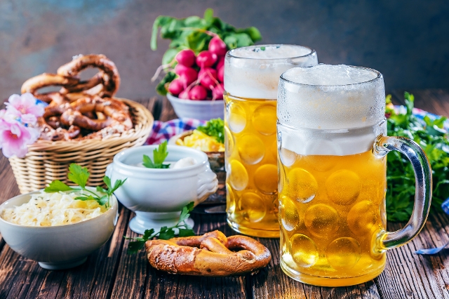 Typisches Oktoberfest-Essen auf einem Tisch: Bier, Brezen, Radieschen und Sauerkraut