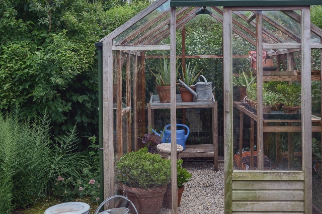 Das Gewächshaus aus Holz passt gut in den Garten