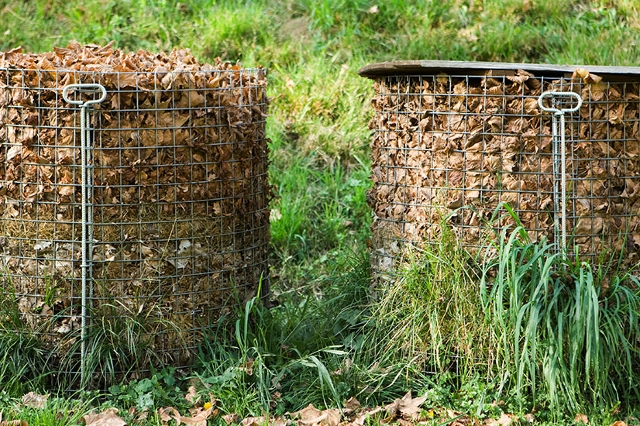 Drahtkomposter im Garten gefüllt mit Herbstlaub auf einer Wiese.
