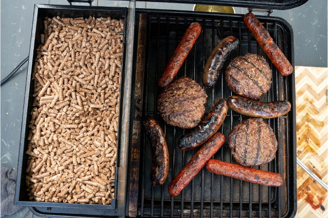 Pelletgrill im Einsatz – Grillgut liegt auf dem Rost, Holzpellets sichtbar im Vorratsbehälter