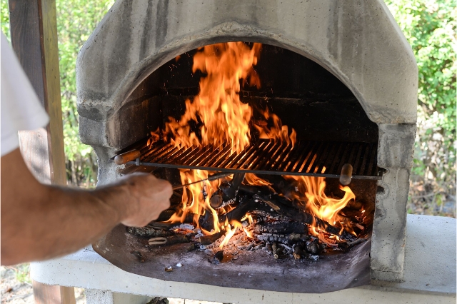 Grillen im Gartenkamin: Ein Mann platziert das Gitter für das Grillgut