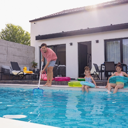 Mann reinigt Pool mit Kescher für zwei Mädels