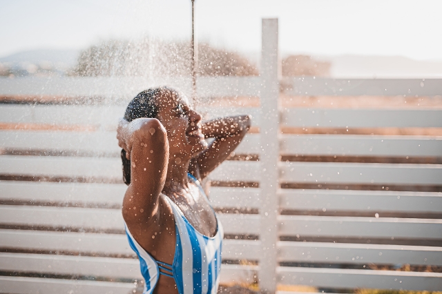 Junge Frau unter Wasserstrahl einer Solardusche