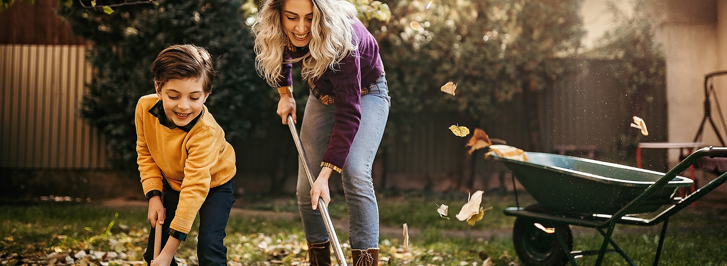 Mutter und Sohn pflegen Rasen im Herbst