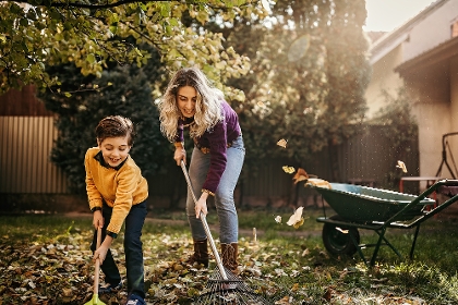 Mutter und Sohn pflegen Rasen im Herbst