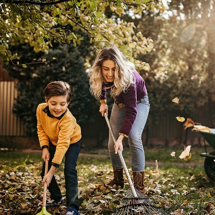 Mutter und Sohn pflegen Rasen im Herbst
