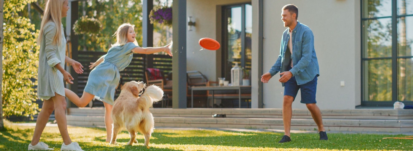 Familie spielt Frisbee auf unkrautfreiem Rasen im Garten