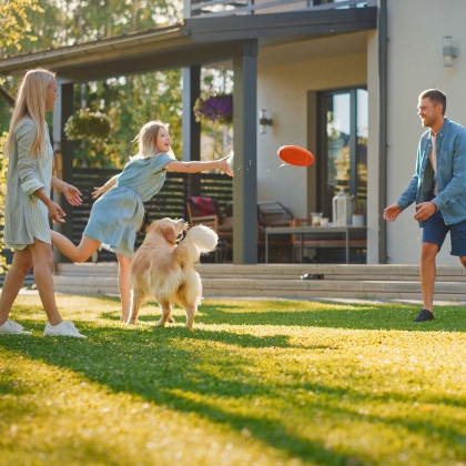 Familie spielt Frisbee auf unkrautfreiem Rasen im Garten