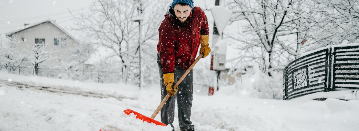Mann räumt Gehweg mit Schneeschaufel