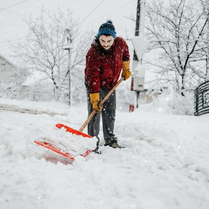 Mann räumt Gehweg mit Schneeschaufel
