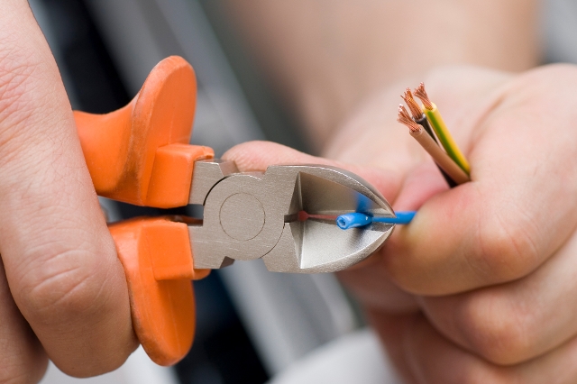 Jemand schneidet mit einem Seitenschneider ein Kabel durch