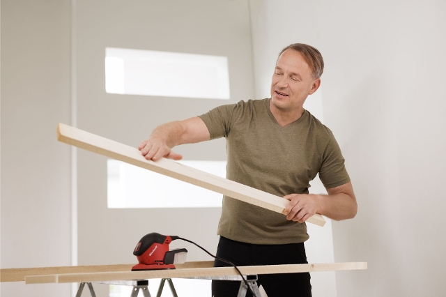 Handwerker zeigt frisch geschliffenes Holz