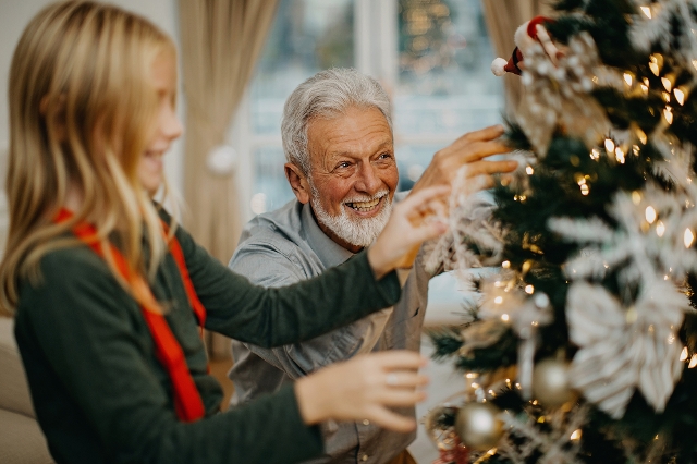 Älterer Mann und junges Mädchen schmücken Weihnachtsbaum