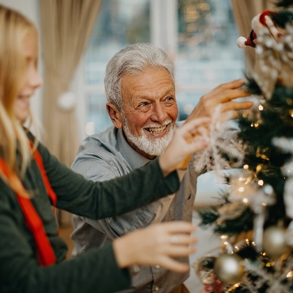 Älterer Mann und junges Mädchen schmücken Weihnachtsbaum