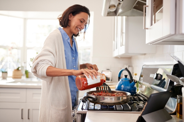 Frau kocht mit selbst eingekochtem Tomatensugo