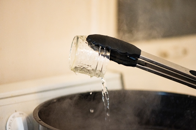 Glas wird mit Zange aus heißem Wasserbad geholt
