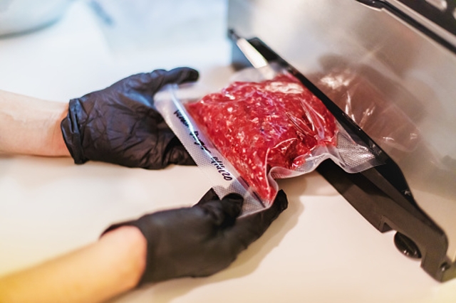 Person vakuumiert Faschiertes im Vakuumiergerät